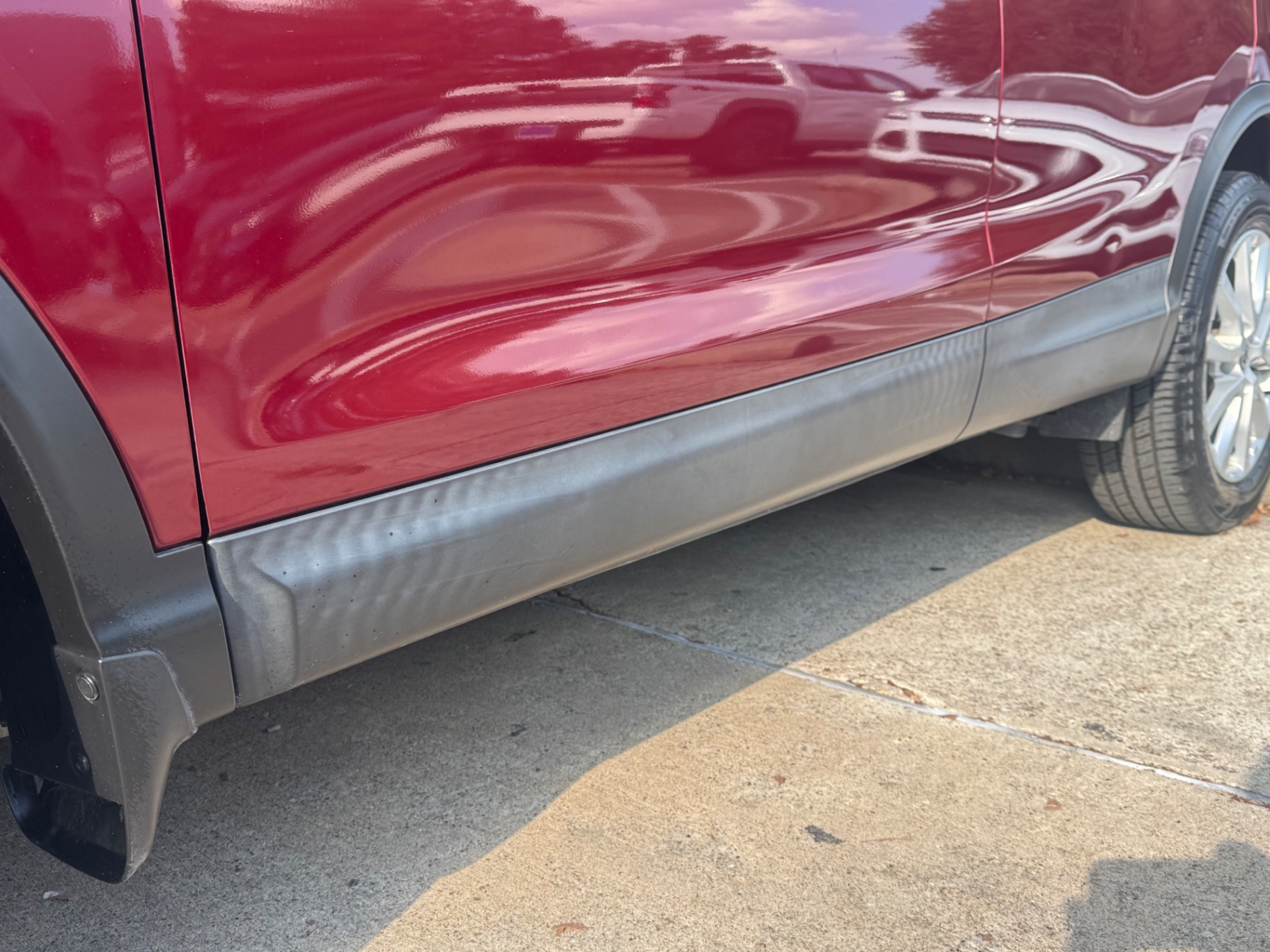 Before photo of faded gray rocker panel cladding on red SUV